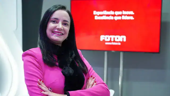 Imagem de uma mulher sorridente com blazer rosa na feira de tecnologia financeira.